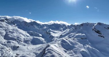 Karla kaplı dağların, güneşli gökyüzünün ve kayak, snowboard, yürüyüş ve açık hava maceraları için mükemmel manzaralı yamaçların nefes kesici hava manzarası.