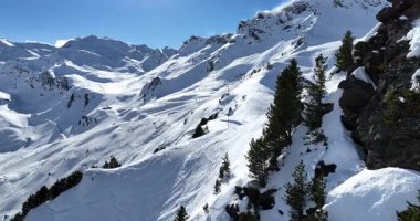 Karla kaplı dağların, güneşli gökyüzünün ve kayak, snowboard, yürüyüş ve açık hava maceraları için mükemmel manzaralı yamaçların nefes kesici hava manzarası.