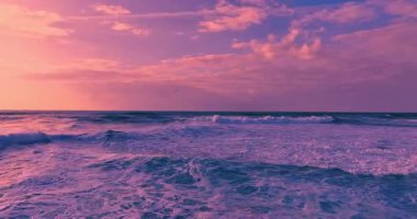 Güneş batarken kayalık bir kıyıya çarpan derin mavi okyanus dalgalarının dramatik hava manzarası bu sakin tropikal deniz manzarasını güzelleştirir. Seyahat, tatil ve doğa temaları için mükemmeldir..