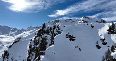 Karla kaplı dağların, güneşli gökyüzünün ve kayak, snowboard, yürüyüş ve açık hava maceraları için mükemmel manzaralı yamaçların nefes kesici hava manzarası.