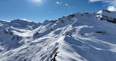 Karla kaplı dağların, güneşli gökyüzünün ve kayak, snowboard, yürüyüş ve açık hava maceraları için mükemmel manzaralı yamaçların nefes kesici hava manzarası.