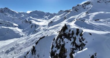 Karla kaplı dağların, güneşli gökyüzünün ve kayak, snowboard, yürüyüş ve açık hava maceraları için mükemmel manzaralı yamaçların nefes kesici hava manzarası.