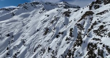 Karla kaplı dağların, güneşli gökyüzünün ve kayak, snowboard, yürüyüş ve açık hava maceraları için mükemmel manzaralı yamaçların nefes kesici hava manzarası.