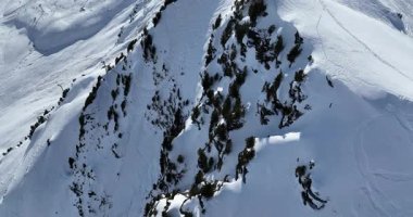 Karla kaplı dağların, güneşli gökyüzünün ve kayak, snowboard, yürüyüş ve açık hava maceraları için mükemmel manzaralı yamaçların nefes kesici hava manzarası.