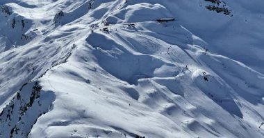 Karla kaplı dağların, güneşli gökyüzünün ve kayak, snowboard, yürüyüş ve açık hava maceraları için mükemmel manzaralı yamaçların nefes kesici hava manzarası.