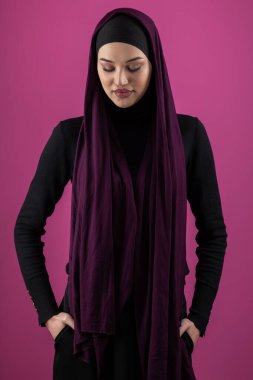 Başörtülü çarpıcı bir Müslüman kadın zarif bir şekilde stüdyoda pembe bir arka plana karşı poz veriyor, zarafet ve güven yayıyor.. 