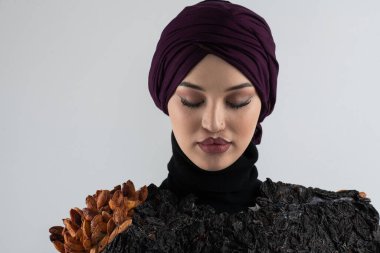 Türbanlı şık bir Müslüman kadın, profesyonel bir stüdyoda kurutulmuş eriklerden yapılan el yapımı moda aksesuarını sunar. Bir tesettürdeki Müslüman kadın, benzersiz el yapımı aksesuarını gururla sergiler.