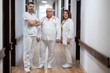 Bir grup deneyimli doktor hastane koridorunda duruyor. Yorgun ama hastalarla uzun bir günden sonra kendilerini adamışlar.