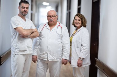 Bir grup deneyimli doktor hastane koridorunda duruyor. Yorgun ama hastalarla uzun bir günden sonra kendilerini adamışlar.