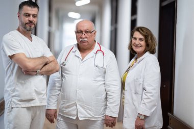 Bir grup deneyimli doktor hastane koridorunda duruyor. Yorgun ama hastalarla uzun bir günden sonra kendilerini adamışlar.