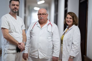 Bir grup deneyimli doktor hastane koridorunda duruyor. Yorgun ama hastalarla uzun bir günden sonra kendilerini adamışlar.