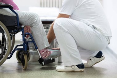 Kıdemli kadın gülümseyen bir terapistin yardımıyla fiziksel egzersiz yapıyor. Yaşlıların rehabilitasyonu ve hareket düzelmesi kavramı.