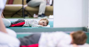 Fizyoterapi seansı sırasında terapi minderinde küçük bir çocuk, denetimli esneme aktivitesiyle meşgul oluyor..