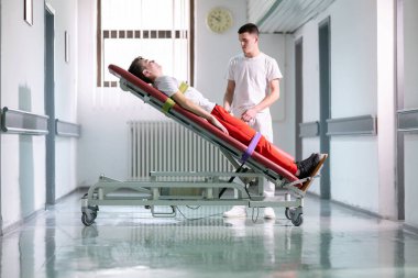 Erkek terapist, klinik koridordaki bir rehabilitasyon sırasında ayakta duran bir çerçeveyle hastaya yardım ediyor. Fiziksel iyileşme desteği kavramı.