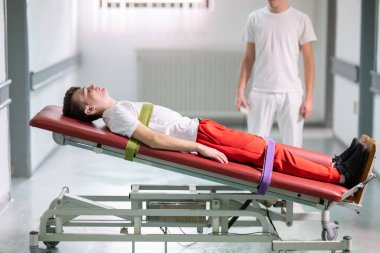 Erkek terapist, klinik koridordaki bir rehabilitasyon sırasında ayakta duran bir çerçeveyle hastaya yardım ediyor. Fiziksel iyileşme desteği kavramı.