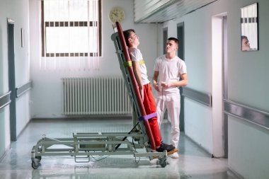 Erkek terapist, klinik koridordaki bir rehabilitasyon sırasında ayakta duran bir çerçeveyle hastaya yardım ediyor. Fiziksel iyileşme desteği kavramı.