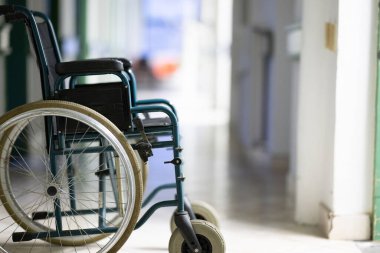 Parlak bir hastane koridorunda sahipsiz tekerlekli sandalye var. Erişilebilirlik ve hasta taşımacılığı kavramı.