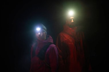 Fenerlerle donatılmış çift, gece havasını kesen ışık huzmeleriyle zifiri karanlıkta bir ormanı keşfediyor..