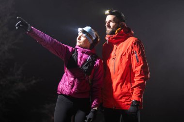 Bir kadın, kruvazör farlarının altında yürüyüş partneriyle yol tarifi tartışırken mesafeyi işaret eder.