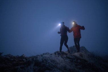 İki sporcu gece boyunca engebeli dağ patikalarında koşar, far ve kış giysileri giyerek, soğuk, sisli arazide kararlılık ve dayanıklılıkla yol alırlar..
