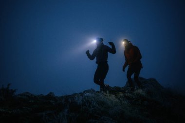 İki sporcu gece boyunca engebeli dağ patikalarında koşar, far ve kış giysileri giyerek, soğuk, sisli arazide kararlılık ve dayanıklılıkla yol alırlar..