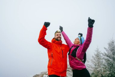 Rocky Peak 'te kutlama yapan iki yürüyüşçü. Gün doğarken engebeli dağ sırtında yumruklarını kaldıran iki yürüyüşçü.