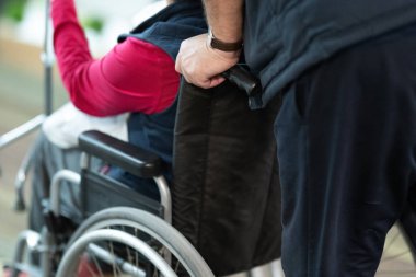 Tekerlekli sandalyedeki birine yardım eden birinin kısmi görüntüsü..