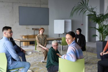 Çeşitli iş adamları modern bir ofiste dikkatle oturup, bir eğitmenin önderliğindeki bir eğitim oturumunda aktif olarak en son teknolojik gelişmelere odaklanırlar.