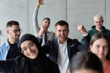 Çeşitli iş adamlarından oluşan bir ekip modern bir ofiste başarılarını coşkuyla kutluyor, amaçlarına ulaştıktan sonra zafer ve birlik içinde olduklarını ifade ediyorlar.. 