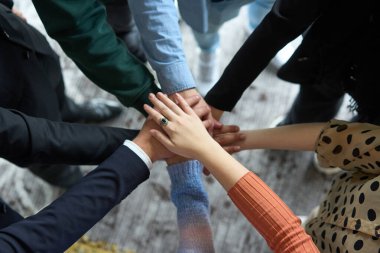 İş adamlarının bir daire içinde el ele tutuşması, birlik, işbirliği ve iş yerinde ortak başarının simgesi..