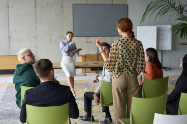 Çeşitli iş adamları modern bir ofiste dikkatle oturup, bir eğitmenin önderliğindeki bir eğitim oturumunda aktif olarak en son teknolojik gelişmelere odaklanırlar.