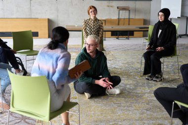 Şirket işletme ekibi bir yönetici veya koçla toplantı yapıyor. Bir grup mutlu, çok ırklı insan bir çemberin içinde oturuyor. .