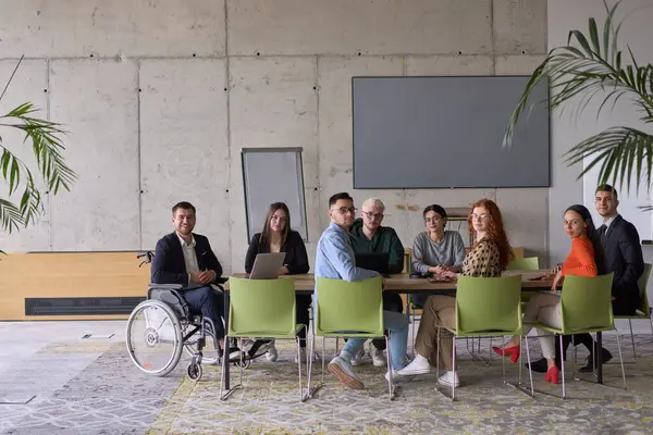 Muhtelif bir grup iş adamı, yöneticileriyle bir ofiste oturuyorlar, şu anda tekerlekli sandalyede, işbirliği, liderlik ve kapsayıcılığı destekliyorlar..