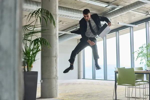 Modern bir ofise kendinden geçmiş bir şekilde atlayan bir işadamı, elinde bir evrak çantasıyla, başarı ve zafer anını kutluyor.