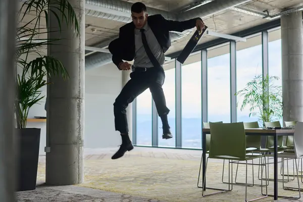 Modern bir ofise kendinden geçmiş bir şekilde atlayan bir işadamı, elinde bir evrak çantasıyla, başarı ve zafer anını kutluyor.