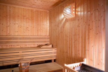 Sıcak ve boş ahşap bir saunanın geniş manzarası. Sarılmış havlular ve rahatlamak için hazırlanmış ahşap banklar..