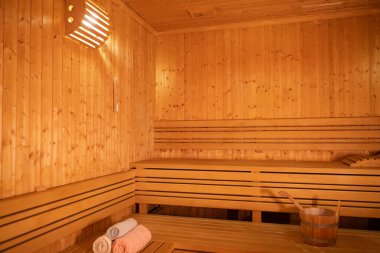 Sıcak ve boş ahşap bir saunanın geniş manzarası. Sarılmış havlular ve rahatlamak için hazırlanmış ahşap banklar..