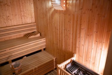 Sıcak ve boş ahşap bir saunanın geniş manzarası. Sarılmış havlular ve rahatlamak için hazırlanmış ahşap banklar..