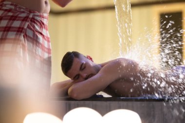 Türk Hamamında Su İşlemi. Geleneksel Türk hamamında su terapisi gören bir adam, süslü detaylarla donatıldı..