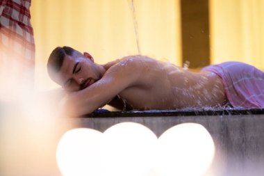 Türk Hamamında Su İşlemi. Geleneksel Türk hamamında su terapisi gören bir adam, süslü detaylarla donatıldı..