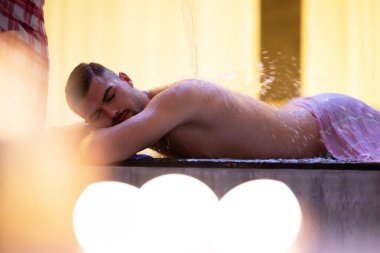 Türk Hamamında Su İşlemi. Geleneksel Türk hamamında su terapisi gören bir adam, süslü detaylarla donatıldı..