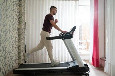 Fiziksel iyileşme programının bir parçası olarak koşu bandında koşan bir adam.