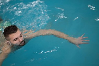 Terapi için yüzüyorum. Profesyonel bir spa merkezinde su terapisi ya da yüzme egzersizi yapan bir adam..