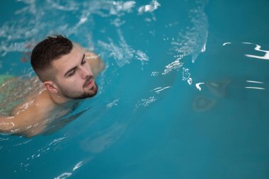 Terapi için yüzüyorum. Profesyonel bir spa merkezinde su terapisi ya da yüzme egzersizi yapan bir adam..