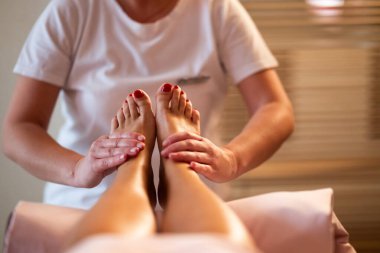 Beyaz üniformalı profesyonel bir masaj terapisti, sakin ve sakin bir spa ortamında müşteriye rahatlatıcı bir ayak masajı sağlar..