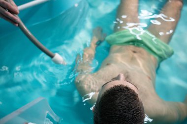 Terapist su ayarlarını ayarlarken adam hidroterapi banyosunda dinleniyor. Terapötik Su Banyosu.