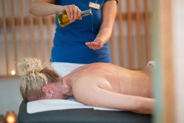 Profesyonel bir masaj terapisti ellerine aromatik yağ dökerek huzurlu bir kaplıca ortamında rahatlatıcı ve canlandırıcı bir masaj seansı hazırlar. 