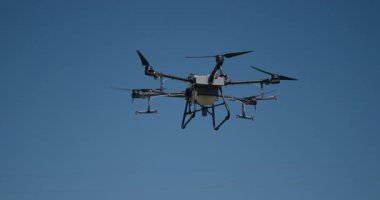 Kırsal ortamlardaki gelişmiş tarım teknolojisi ve hassas tarım tekniklerini vurgulayarak, ekin izleme veya spreyleme görevi sırasında ekili bir tarla üzerinde uçan hava aracı..