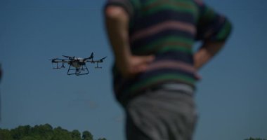 Yenilikçi bir çiftçi, günbatımında bir tarlanın ortasında dikilirken, tarım arazilerini modern akıllı tarım uygulamalarının bir parçası olarak incelemek ve tarlaları izlemek için hava teknolojisini kullanır..