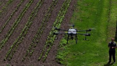 Kırsal ortamlardaki gelişmiş tarım teknolojisi ve hassas tarım tekniklerini vurgulayarak, ekin izleme veya spreyleme görevi sırasında ekili bir tarla üzerinde uçan hava aracı..